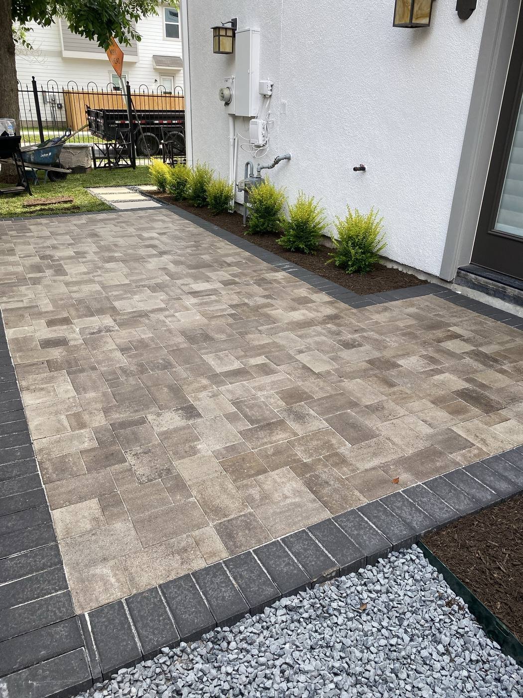 Paver patio with a planted shrub border along the home